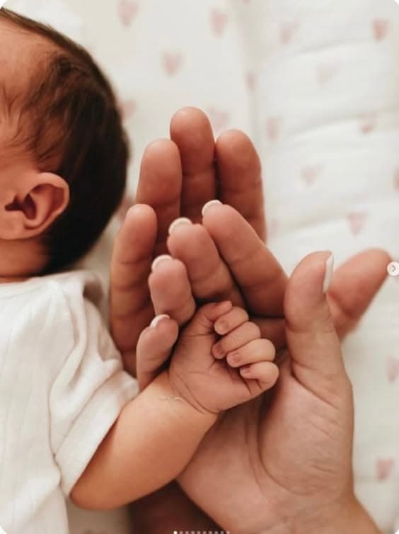 A newborn holding a parent’s fingers, representing fertility and the path to parenthood